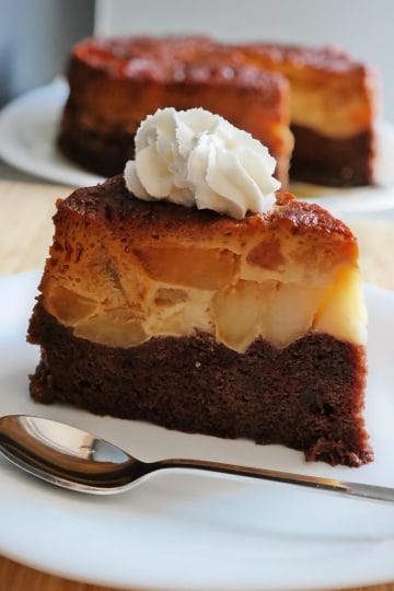 Felie de tort răsturnat cu mere caramelizate, cremă de zahăr ars și blat de cacao, servită cu frișcă